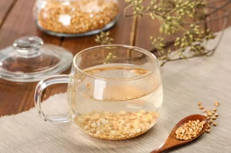 透明茶杯中的糙米茶与木勺里的谷粒